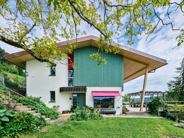 ein Einfamilienhaus mit grünem Holz und einer pinken Markise