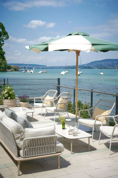 Terrasse des Restaurants Chez Fritz mit modernen Lounge-Möbeln und Blick auf den Zürichsee.