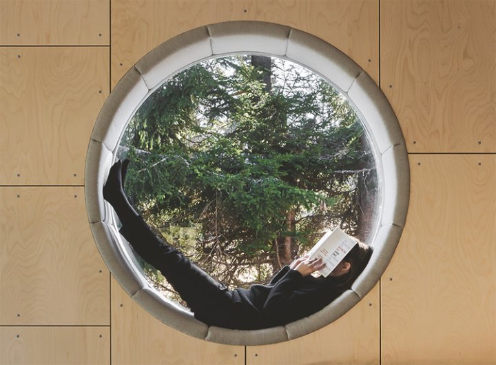 rundes Fenster, in dem eine Frau ein Buch liest