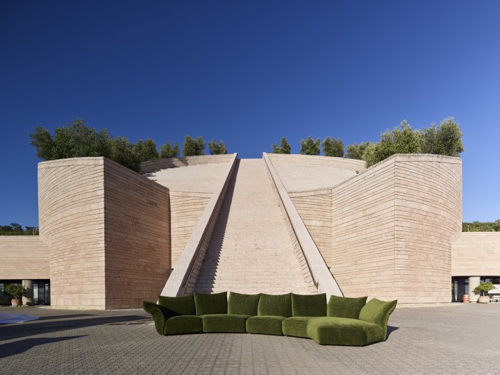 Das intensive Grün Material" des Sofas erinnert mit dem Materials "Every Place" an die Weinreben, die das Weingut umgeben. Im Hintergrund der spektakuläre, zylinderförmige Baukörper mit der Freitreppe.